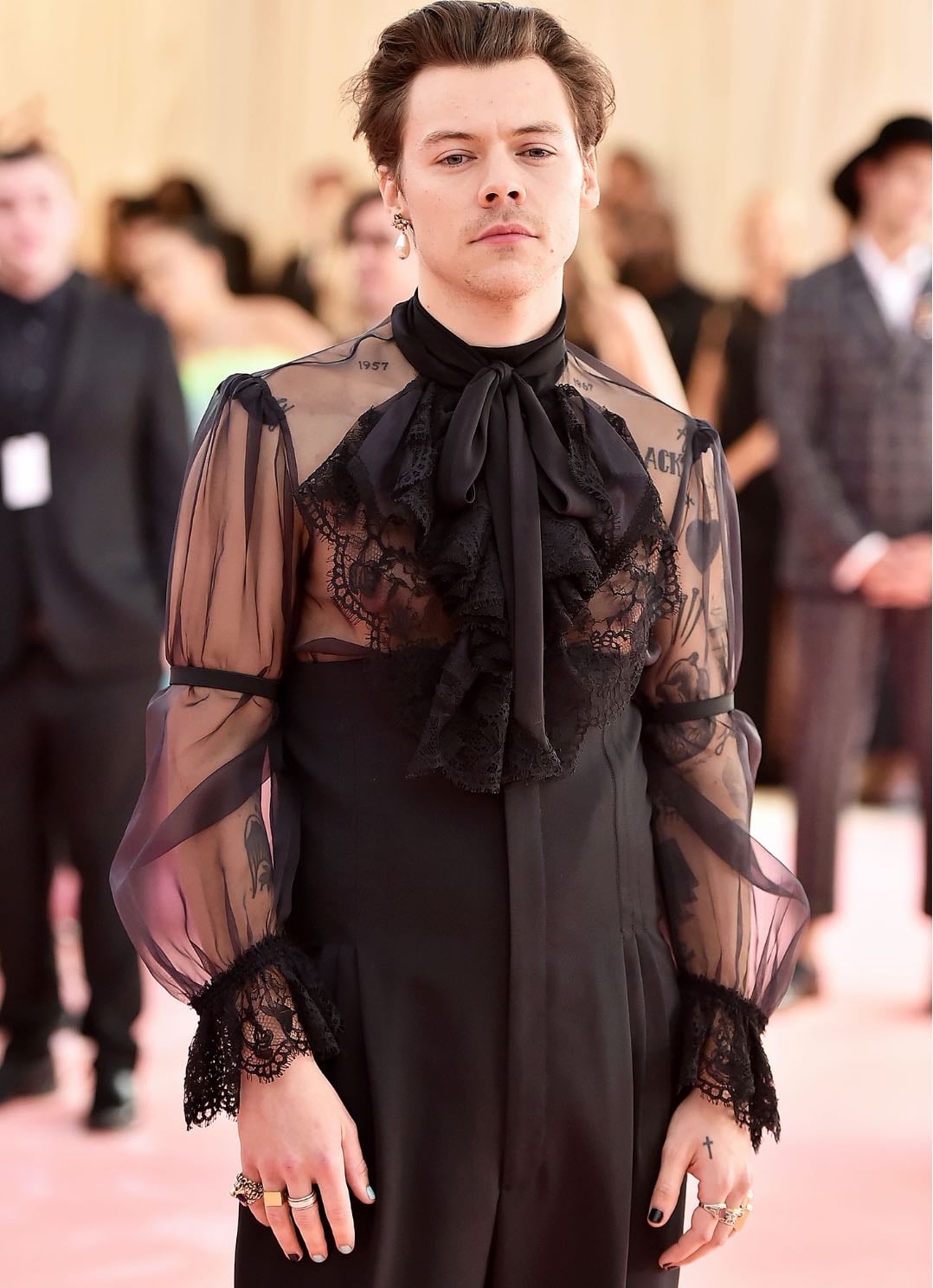 harry styles - custom gucci
designed by alessandro michele. a sheer, black blouse with ruffles and lace, sleek black trousers and a pearl earring
