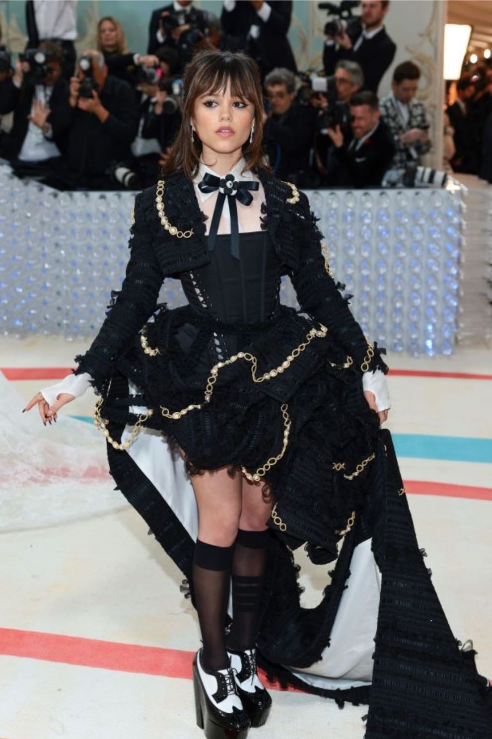 jenna ortega - thom browne
a black corset with a ruffled skirt featuring distressed edges extending into a long train