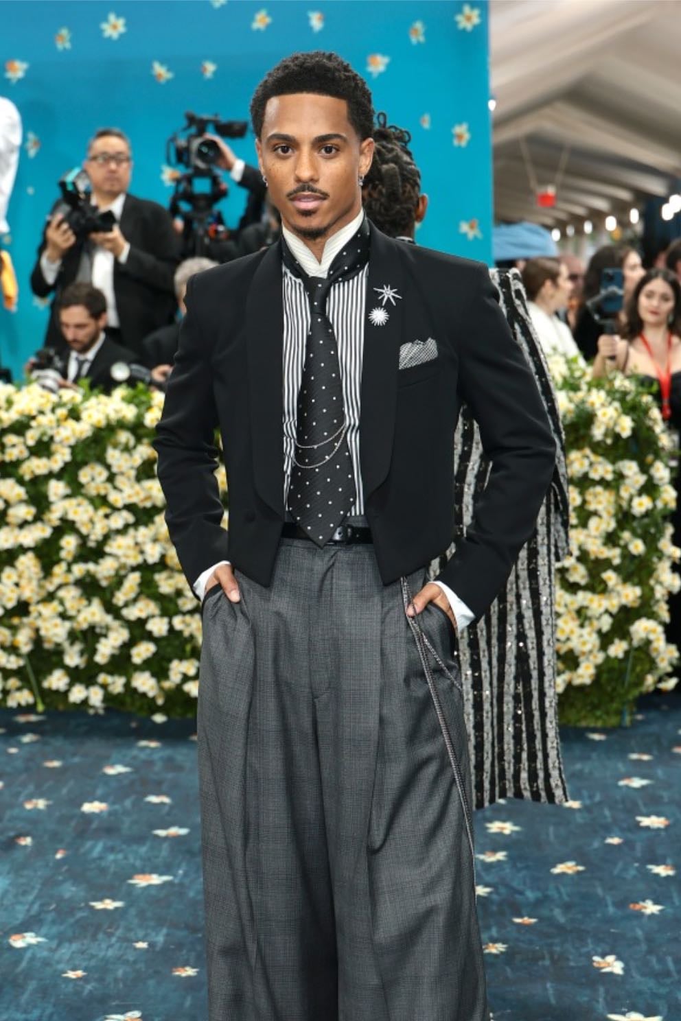 keith powers - boss
a cropped black wool blazer with high-waisted, a striped silk shirt with a polka-dot tie and grey oxford bag-style wide-legged pants, paired with cream calf-leather heeled boots