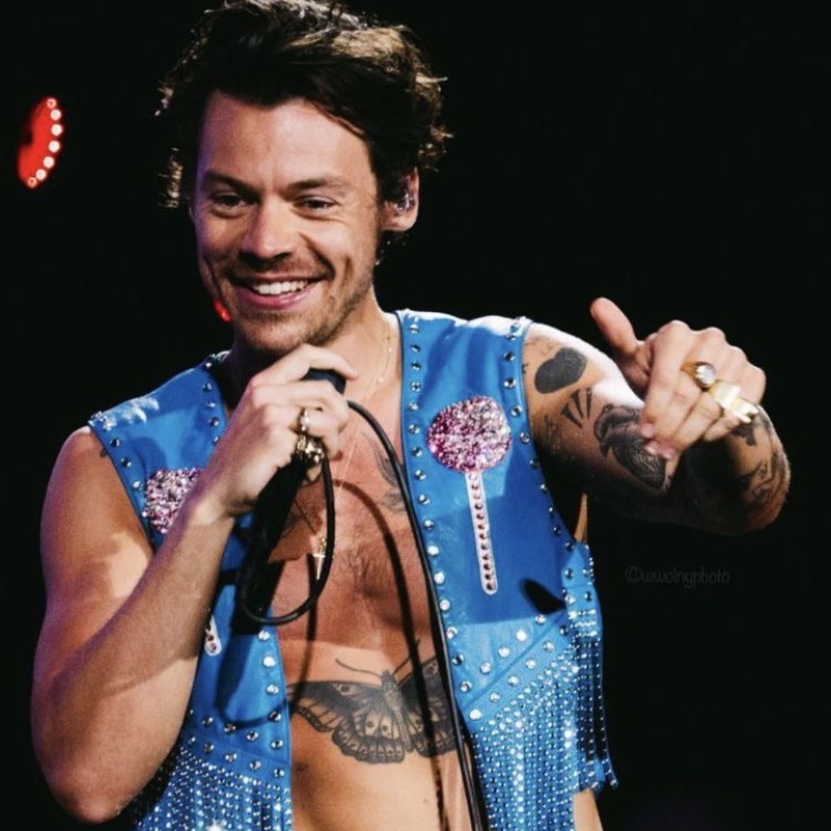 barcelona 07/12/2022 - Black leather pants, no shirt, blue cropped vest with tinsel, rhinestones and pink glittery lollipops, Harry styles in glitter on the back, yellow and red satellite stompers