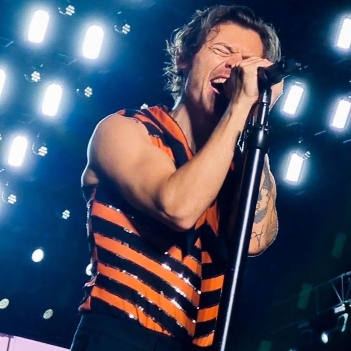 curitiba 12/10/2022 - Black leather pants, orange and black sparkly striped tank top, red satellite stompers