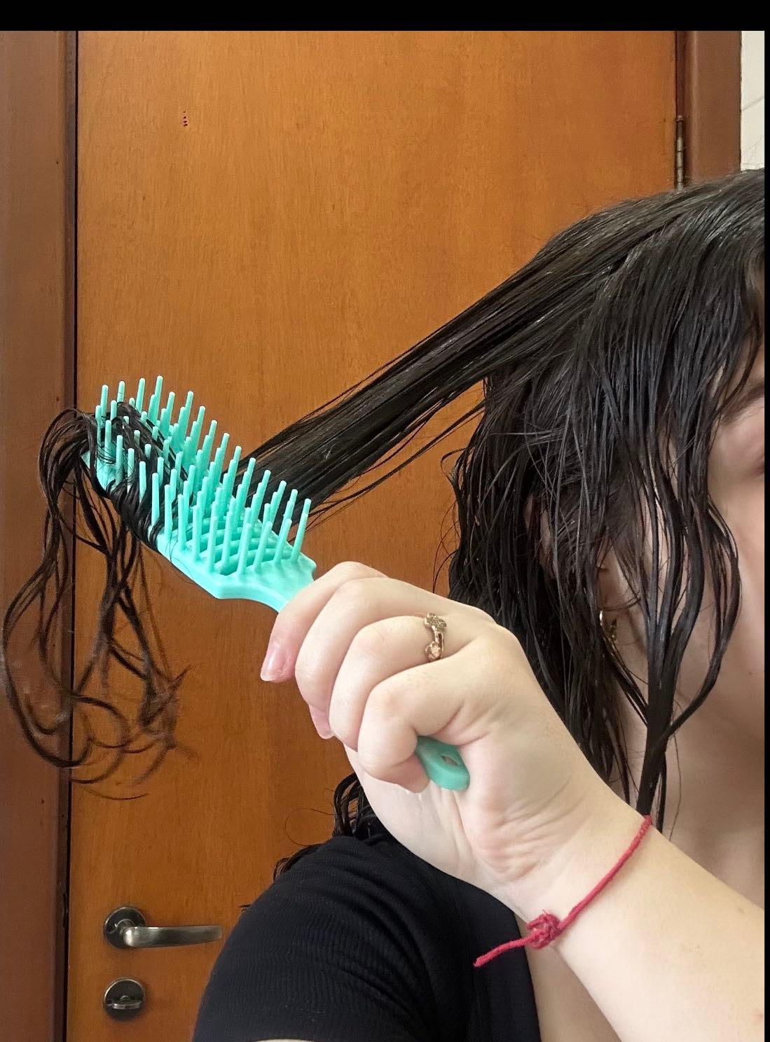 Fitagem (frente) - Agora, eu solto a franja e divido o cabelo na direção do nariz. Em seguida, eu encontro o meio da franja e separo a parte de trás, aplicando o creme ali. Faço a fitagem puxando para o lado, agora, com os dentes da escova virados para trás. Na parte da frente da franja, repito o mesmo processo, depois penteando para a diagonal novamente, repetindo o mesmo processo do outro lado do cabelo