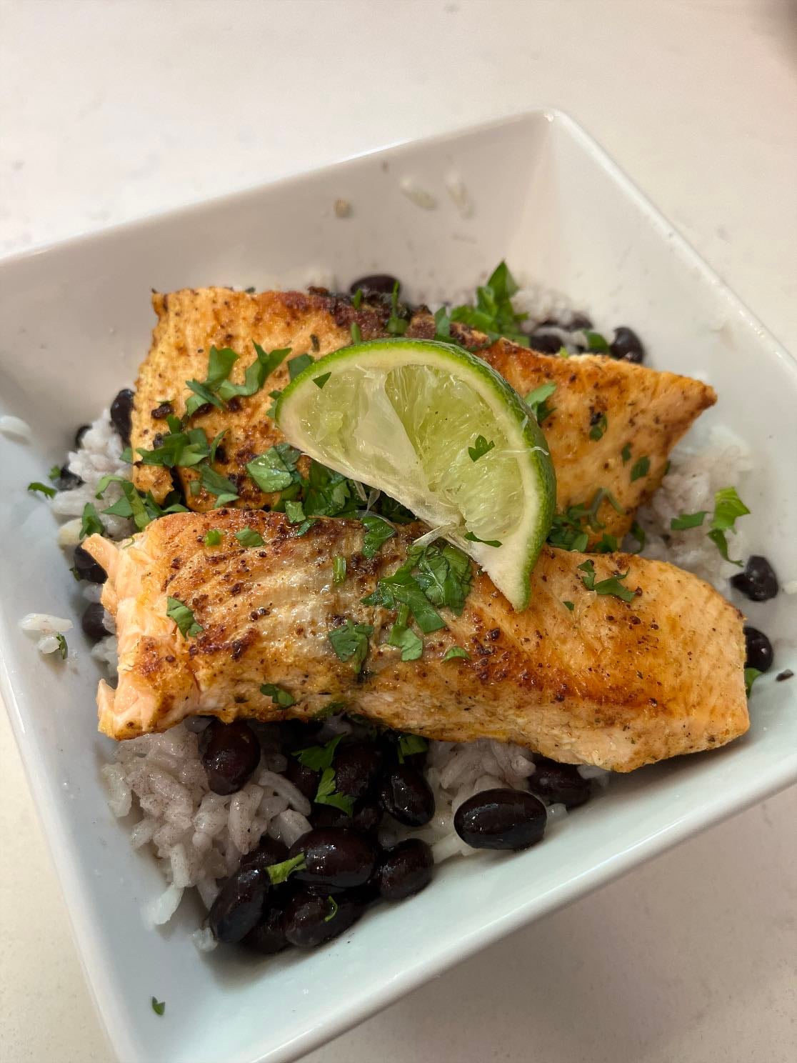 Cali salmon bowl - Grilled with vegan butter: salmon with garlic, paprika, salt, pepper, salmon seasoning, cilantro, and lime. White rice and black beans seasoned with vegan butter, salt, pepper, garlic, lime and cilantro. Topped with cilantro and lime.