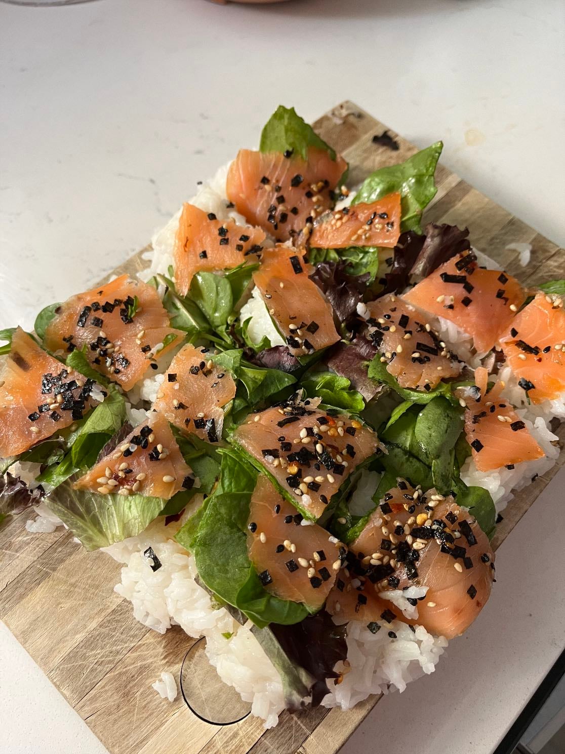 “Sushi” - Rice stored in a square container, topped with spring leaf mix, smoked salmon, sesame oil, chili oil, and furikake