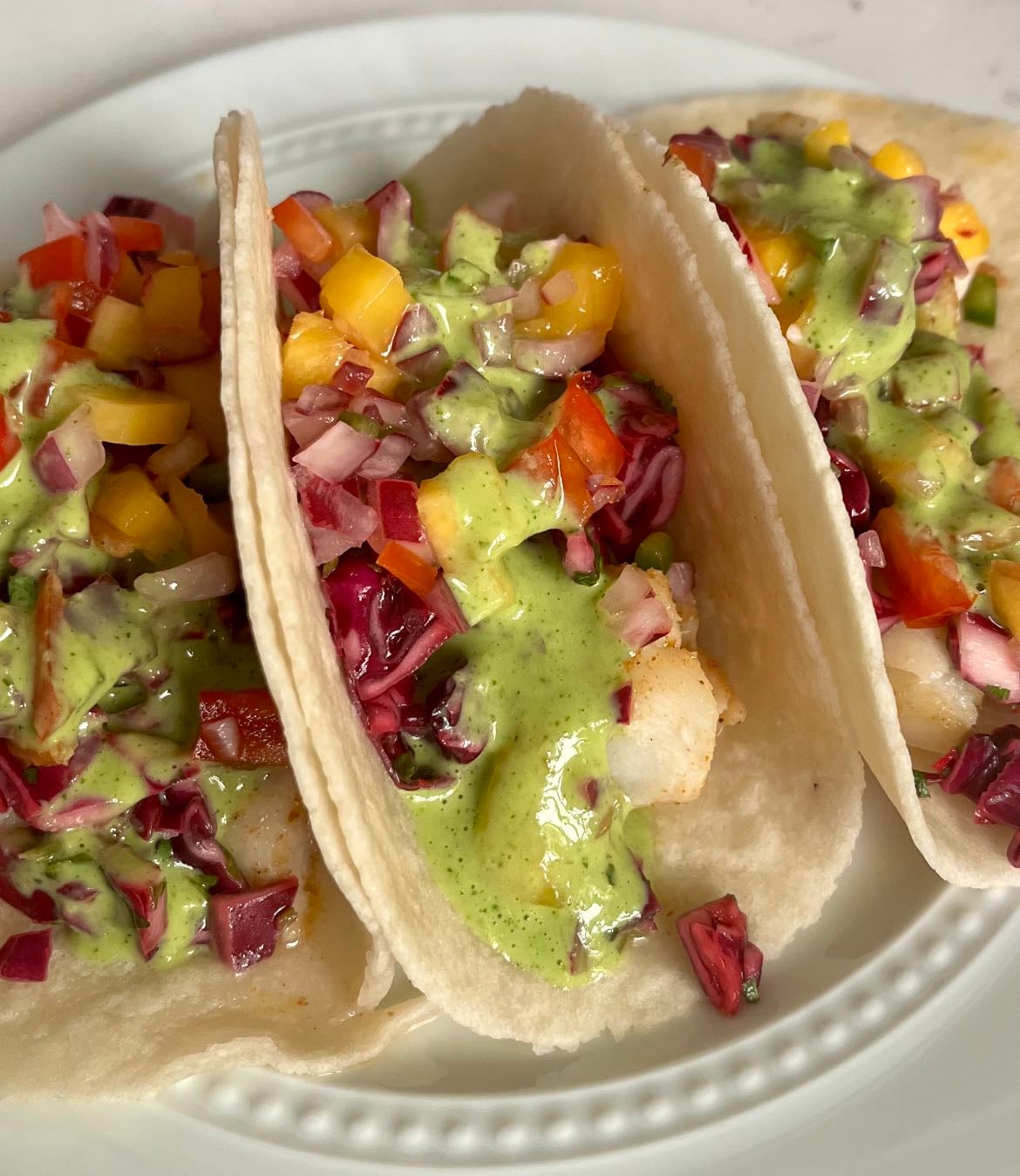 Fish tacos - Cod grilled with vegan butter, salt, pepper, paprika, garlic powder, onion powder, chili powder. Red cabbage slaw. Mango salsa. Jalapeño cilantro sauce. GF taco tortillas.