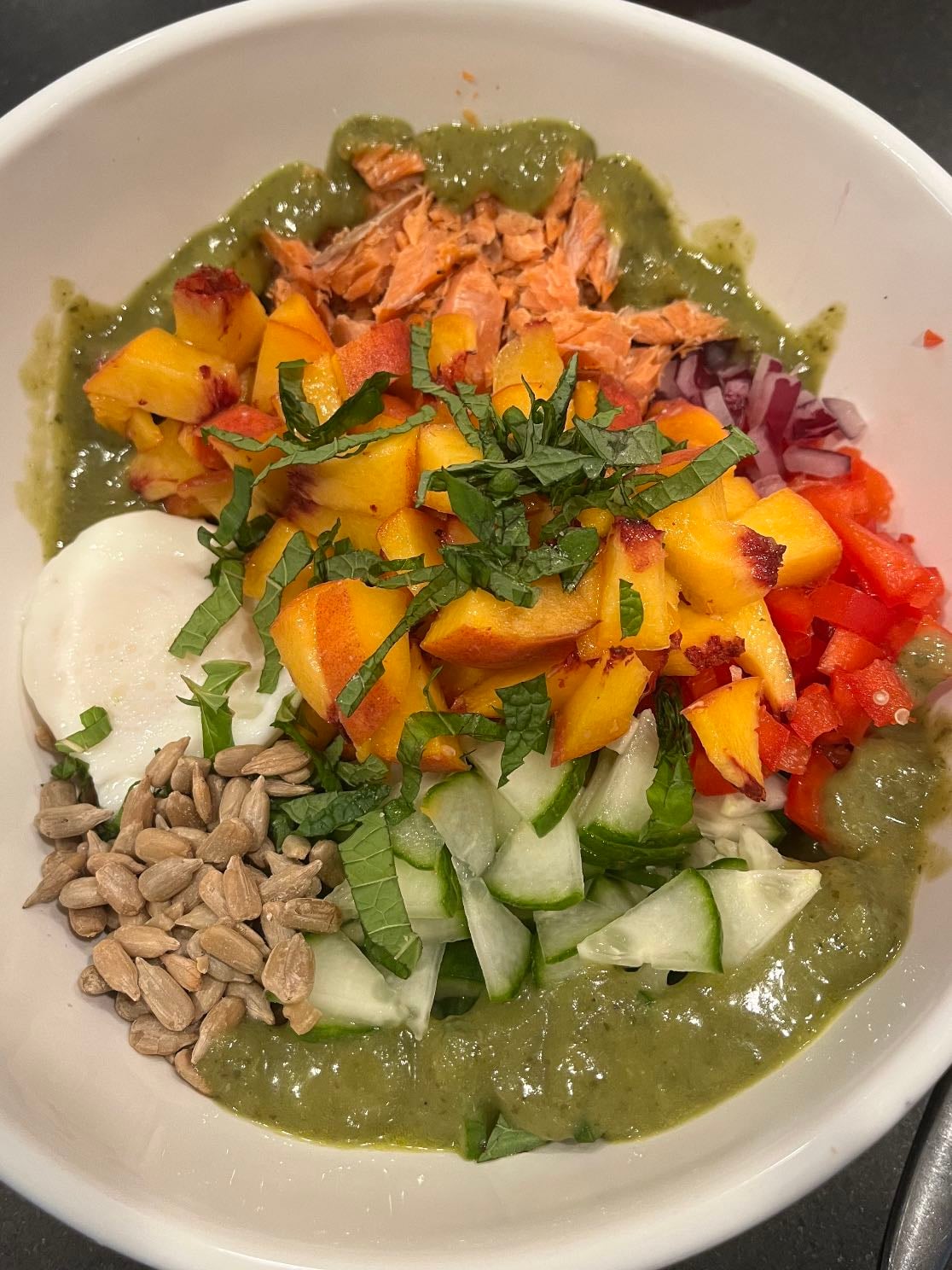 Harvest bowl - Tri-colored quinoa, flakey smoked salmon, cucumber, red pepper, red onion, Boursin, peach, sunflower seeds, poached egg, green goddess dressing, pinch of salt