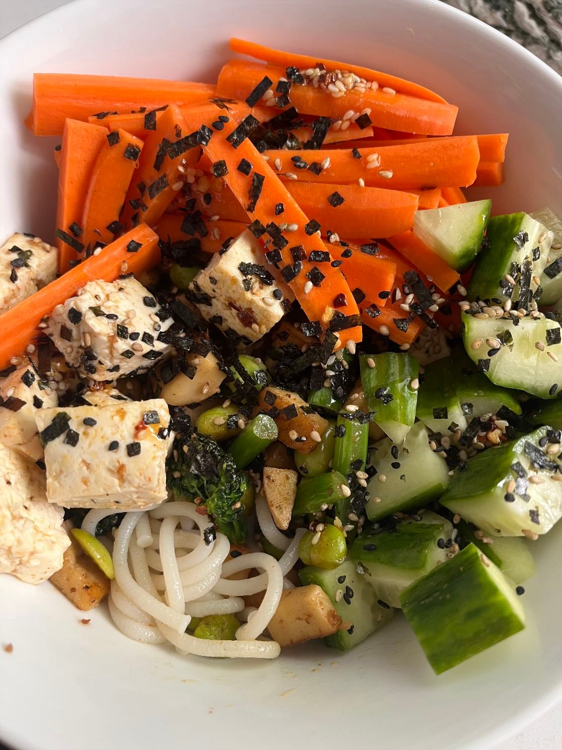 Tofu rice noodle bow - Udon rice noodles, garlic ginger honey tofu, sautéd broccoli and mushrooms, cucumber, carrots, edamame, sesame oil, chili oil, furikake